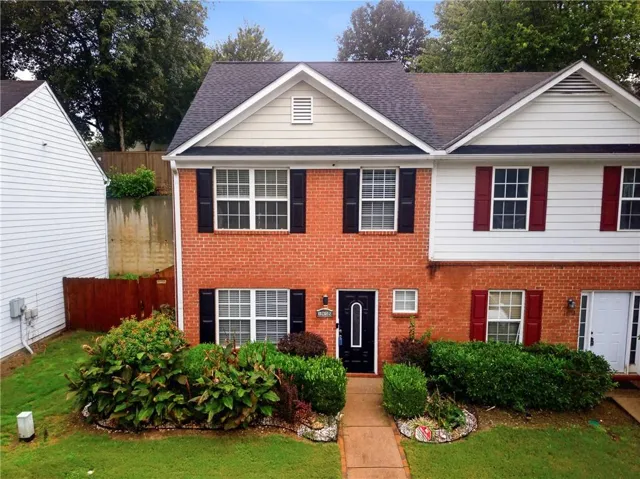 End-unit brick townhome with charming curb appeal and manicured front lawn.
