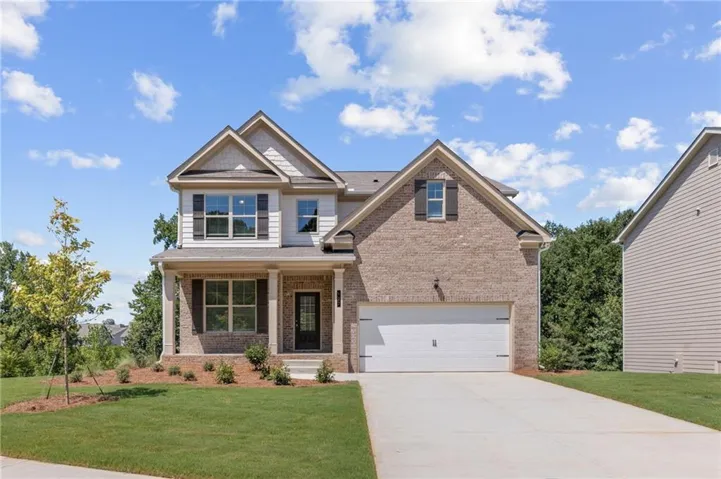 Brick and siding exterior with gabled rooflines, covered front porch, two-car garage, and a concrete driveway