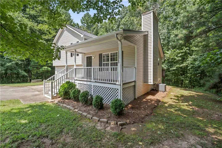 Covered front porch with white railings, light-toned siding, and a prominent chimney