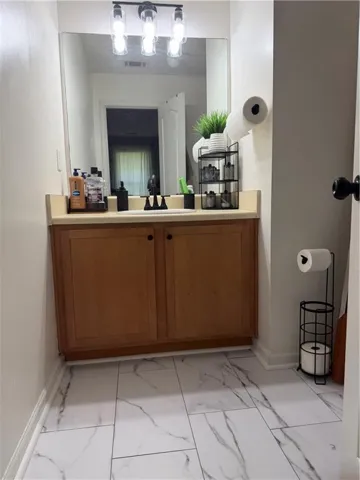 Bathroom featuring wood vanity with integrated sink, light-toned countertop, and rectangular mirror
