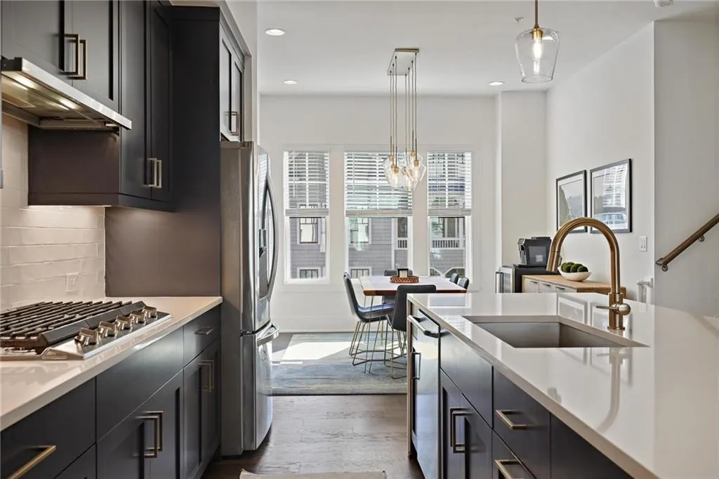 The magazine-worthy kitchen features stainless steel appliances, gas cooktop, double oven, pantry, quartz countertops, and waterfall island.