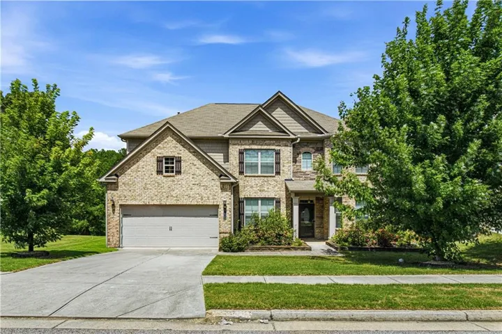 Brick and stone facade, two-car garage, covered entry, and mature landscaping