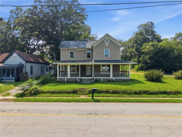 Two-story residence featuring a covered front porch and a prominent front gable with an ornamental window