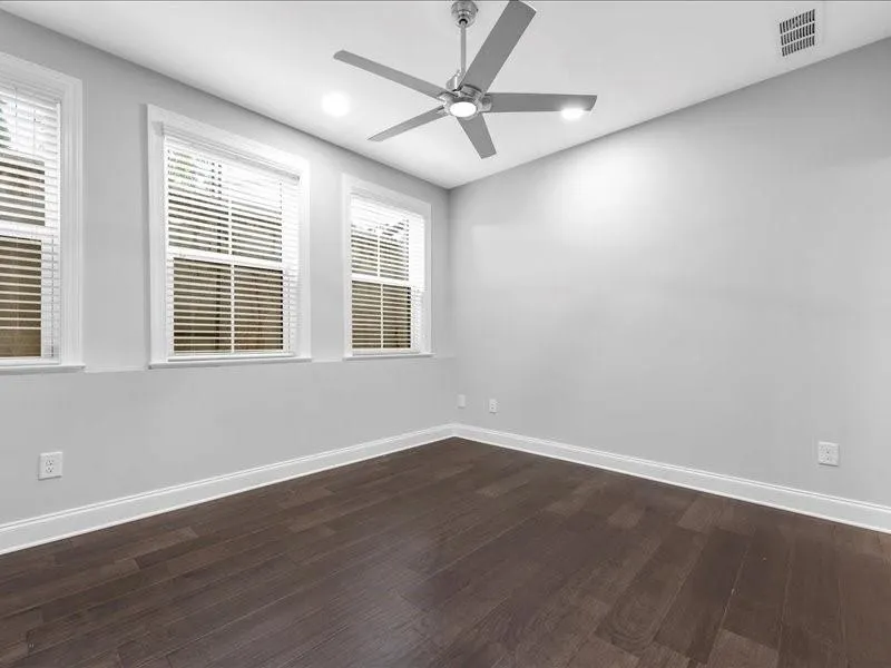 Empty room featuring a ceiling fan, dark wood-type flooring, healthy amount of natural light, and recessed lighting