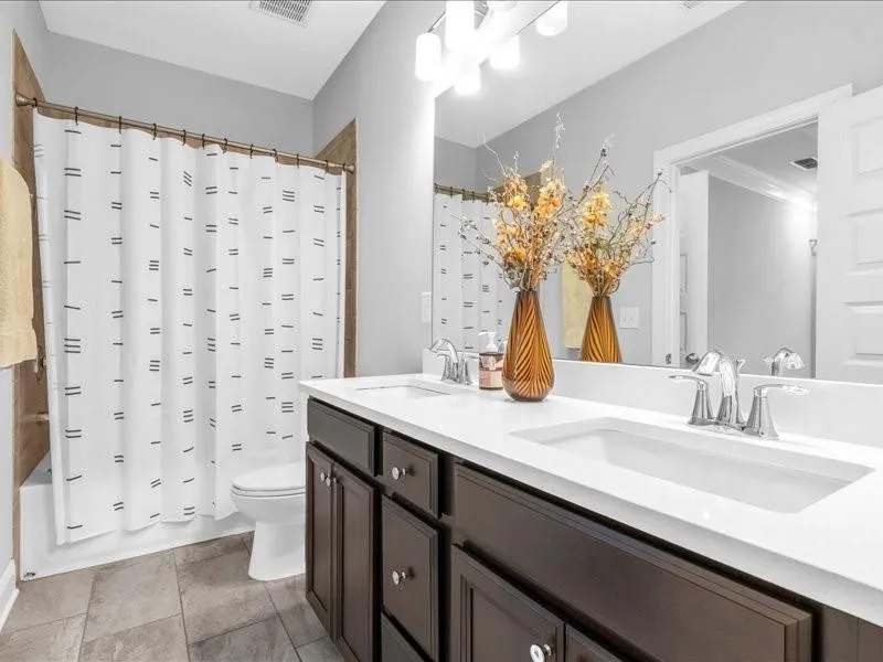 Full bathroom with double vanity and shower / bath combination with curtain