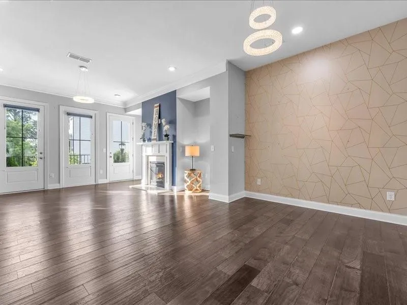 Unfurnished living room with dark wood finished floors, a glass covered fireplace, crown molding, and recessed lighting
