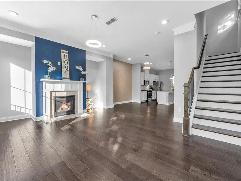 Unfurnished living room with recessed lighting, a glass covered fireplace, dark wood finished floors, stairway, and ornamental molding