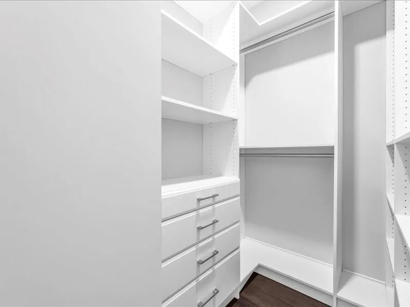 Walk in closet with dark wood-style floors