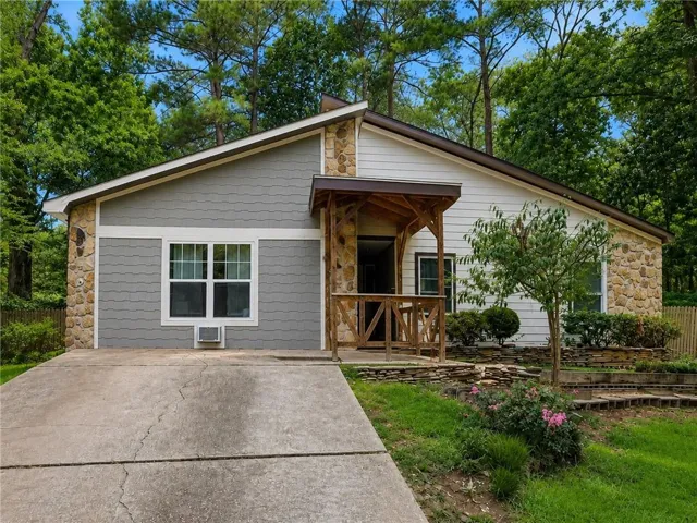 Exterior featuring stone accents, horizontal siding, a covered entry with wood railings, and a sloped roofline