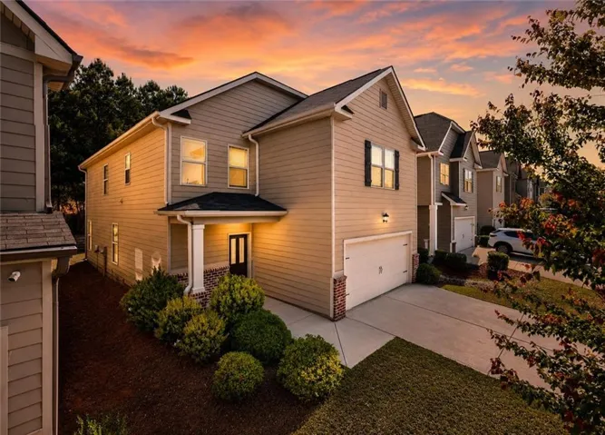 Siding exterior with a covered front entry, brick accent column, and attached garage