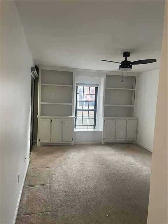 Unfurnished living room with light carpet, ceiling fan, and baseboards