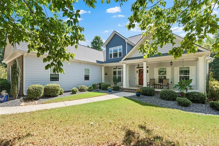 Expansive front yard featuring a manicured lawn, established landscaping, and a concrete walkway