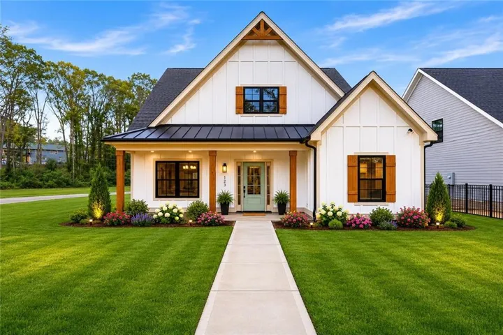 Modern farmhouse exterior featuring white board and batten siding, a black shingle roof, and a turquoise front door