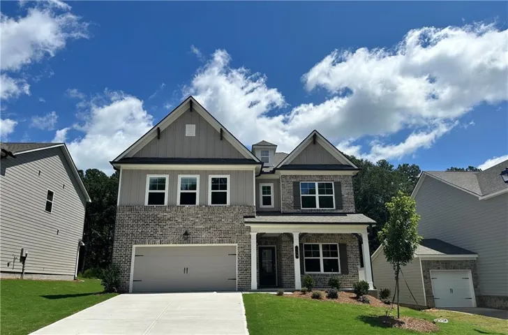 Two-story exterior featuring brick and siding, a two-car garage, and a covered porch with columns