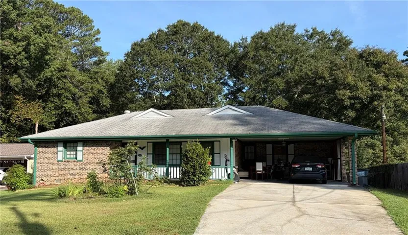 Brick exterior with white siding accents, covered carport, dormer roof details, and a concrete driveway
