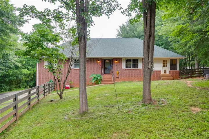 Charming brick exterior with a welcoming front entrance and peaceful wooded setting.