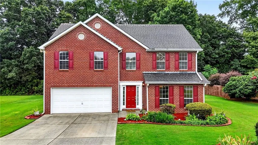 Brick exterior with red shutters, attached two-car garage, and a red front door