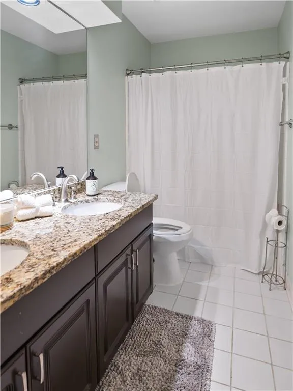 Bathroom with double vanity, toilet, and tile patterned flooring