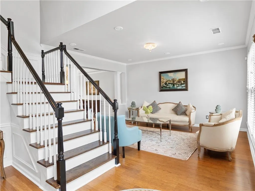 Stairs with light hardwood / wood-style flooring and crown molding