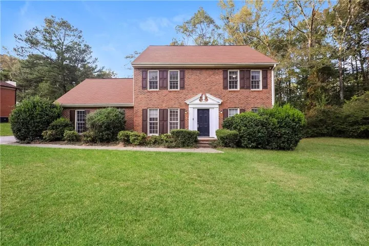 Colonial home with a front yard and brick siding