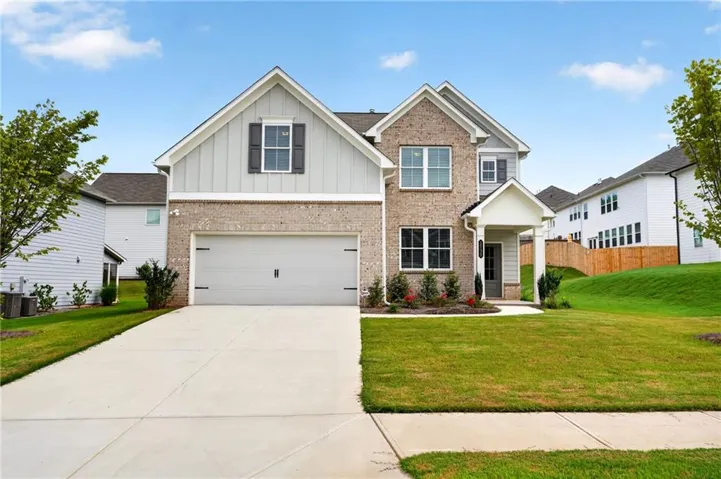 Brick and siding exterior with a covered entry, two-car garage, and established landscaping