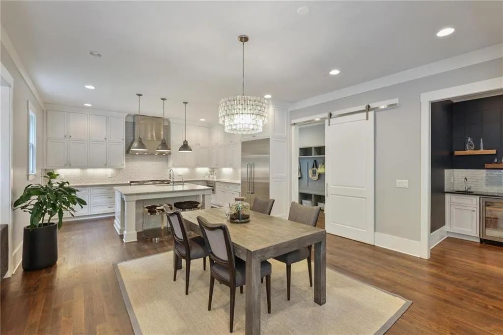 Dining room with sink, a barn door, beverage cooler, dark hardwood / wood-style flooring, and a notable chandelier