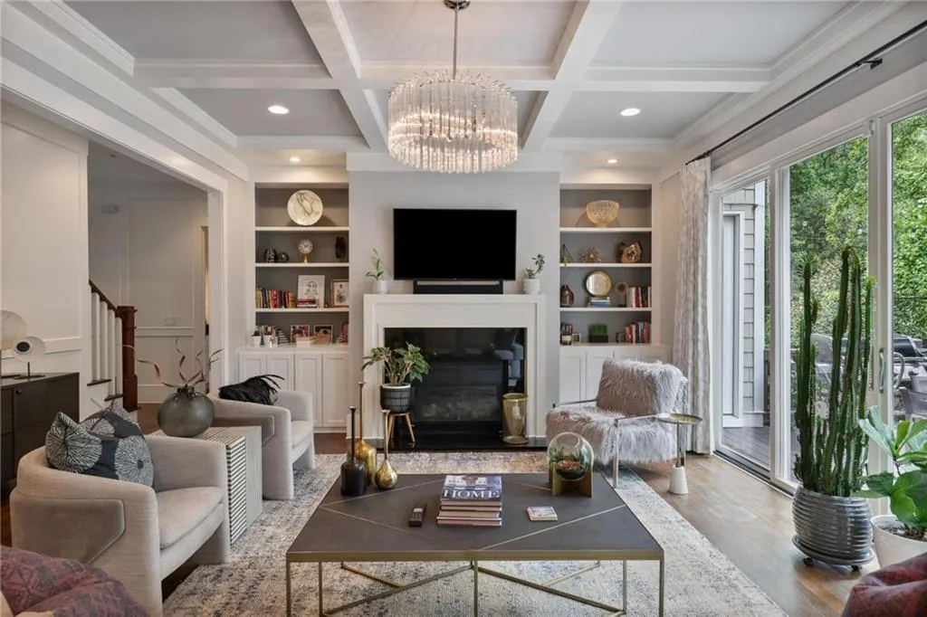 Living room with beam ceiling, light hardwood / wood-style flooring, a chandelier, built in features, and coffered ceiling