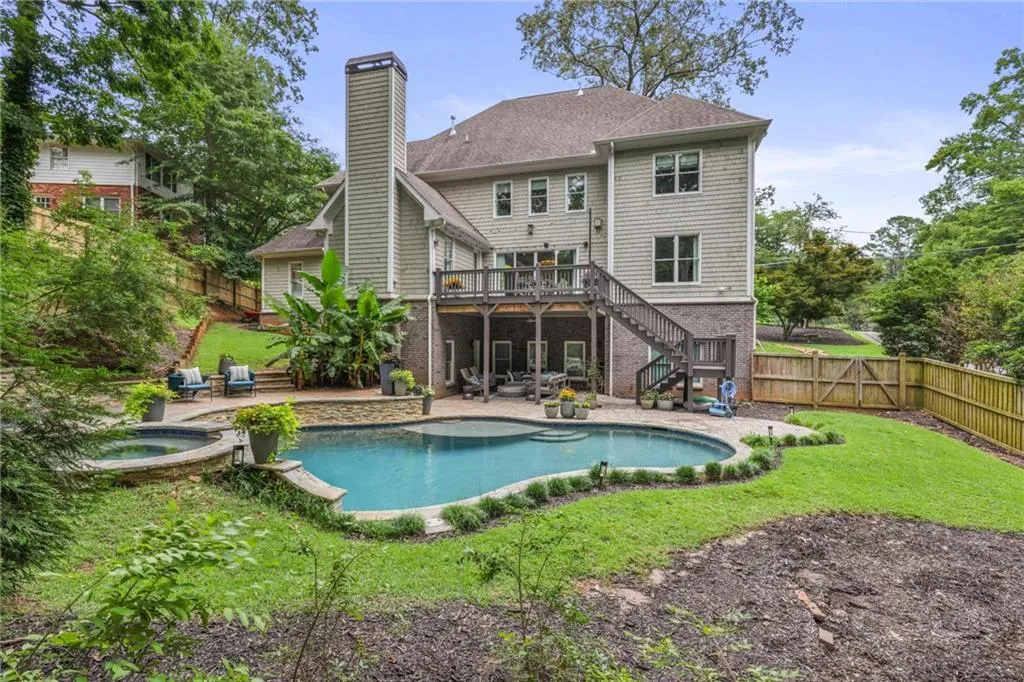 Back of house with a patio, a swimming pool with hot tub, and a lawn