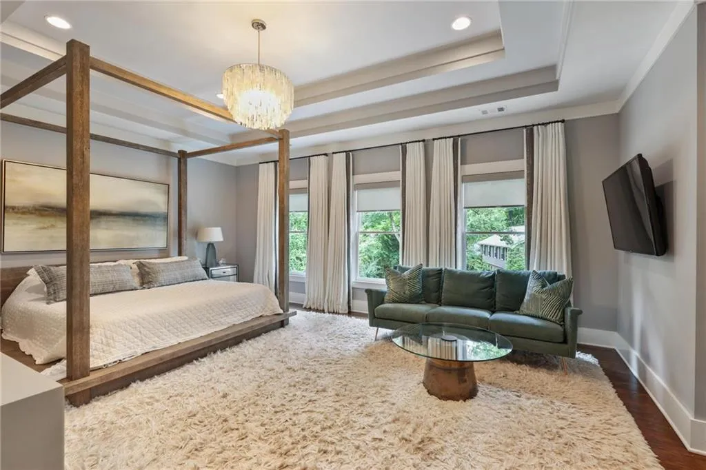 Bedroom featuring dark hardwood / wood-style floors, a raised ceiling, and a notable chandelier