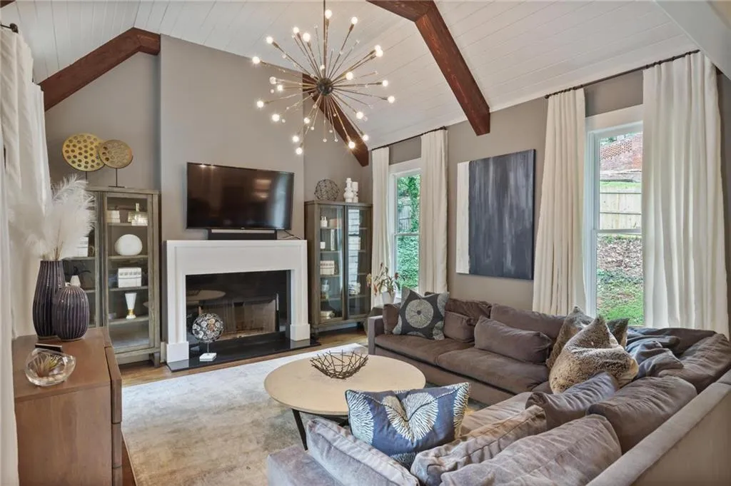Living room featuring beamed ceiling, light hardwood / wood-style floors, plenty of natural light, and a chandelier
