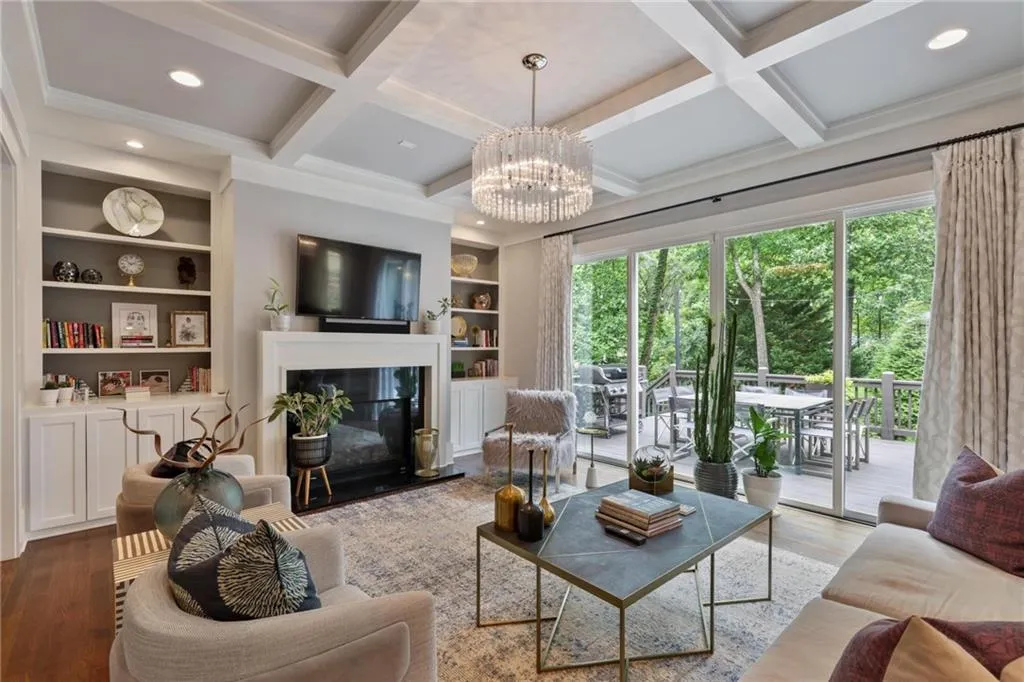 Living room with built in shelves, beam ceiling, light hardwood / wood-style floors, and coffered ceiling