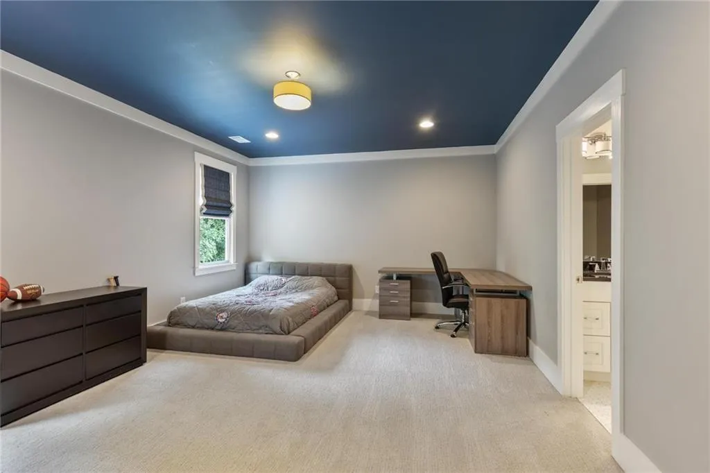 Bedroom with connected bathroom, light colored carpet, and crown molding