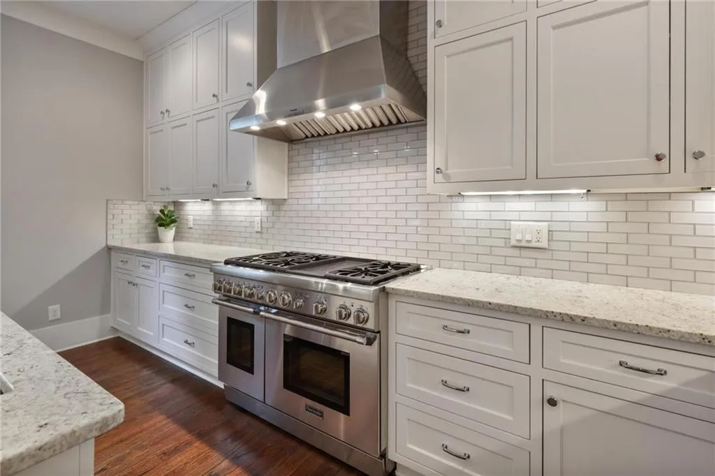 Kitchen featuring white cabinets, wall chimney range hood, double oven range, backsplash, and dark hardwood / wood-style flooring