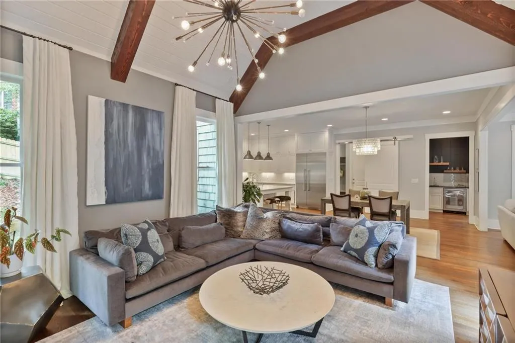 Living room with a chandelier, light hardwood / wood-style flooring, and beam ceiling