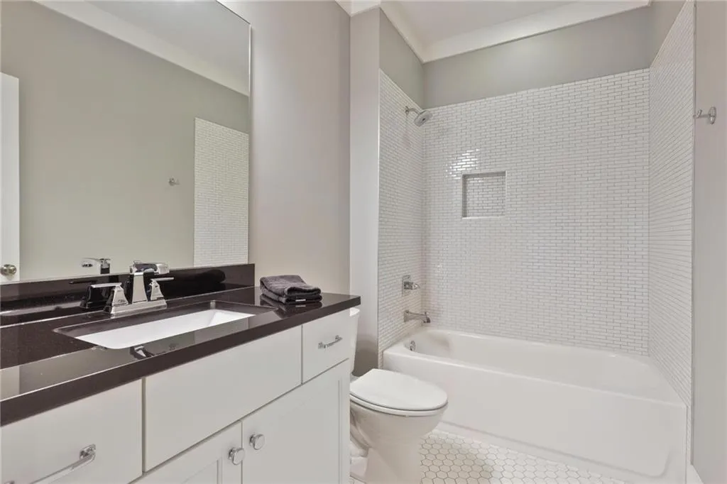 Full bathroom with toilet, tile patterned floors, tiled shower / bath combo, and vanity