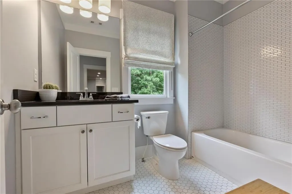 Full bathroom with vanity, tile patterned flooring, tiled shower / bath combo, and toilet