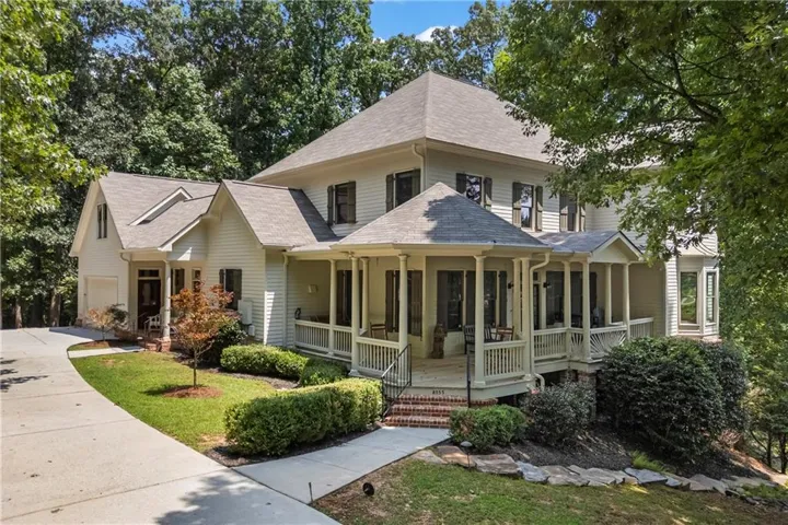 Multi-story residence featuring a covered wrap-around porch with white railings, a multi-gabled roofline, and an attached two-car garage
