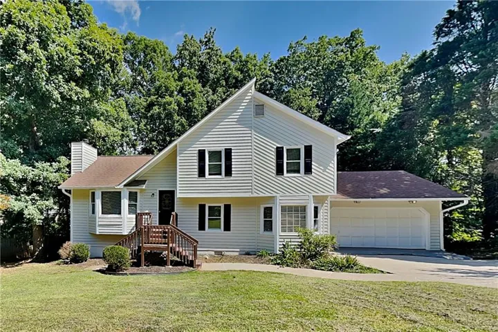 Two-story home with light-colored siding, a prominent two-car garage, and a brown shingle roof