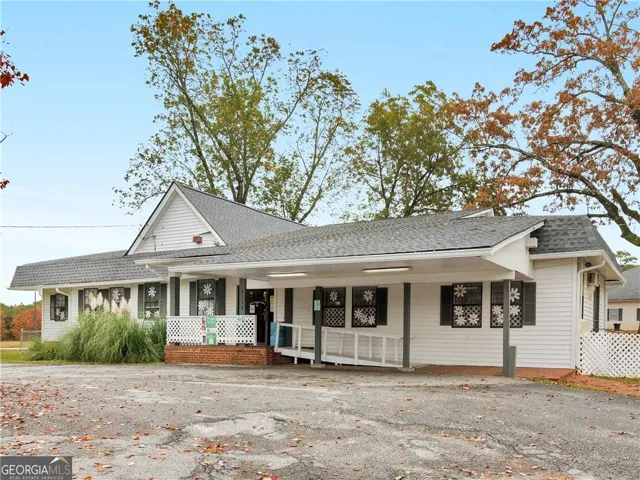 View of front facade with a shingled roof and a porch