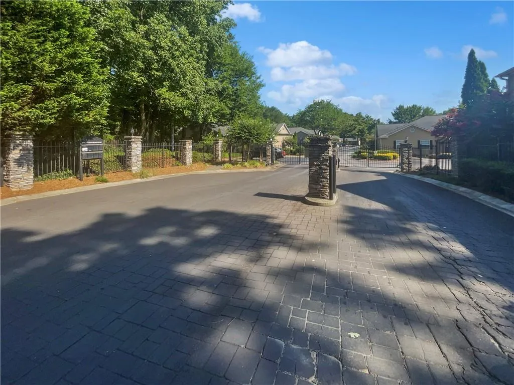 View of street featuring a gate, a gated entry, a residential view, and curbs