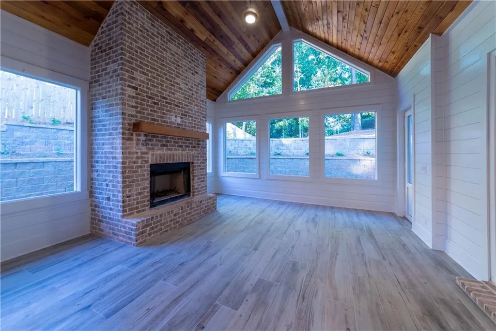 Unfurnished living room featuring a brick fireplace, wood ceiling, and light wood-type flooring
