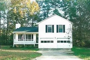 White exterior with dark shutters, covered front porch, and an attached two-car garage
