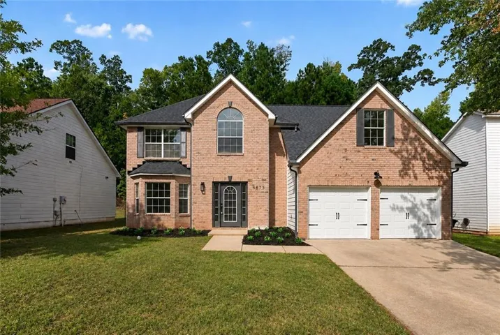 Brick facade with a prominent arched window, bay window, and a two-car garage