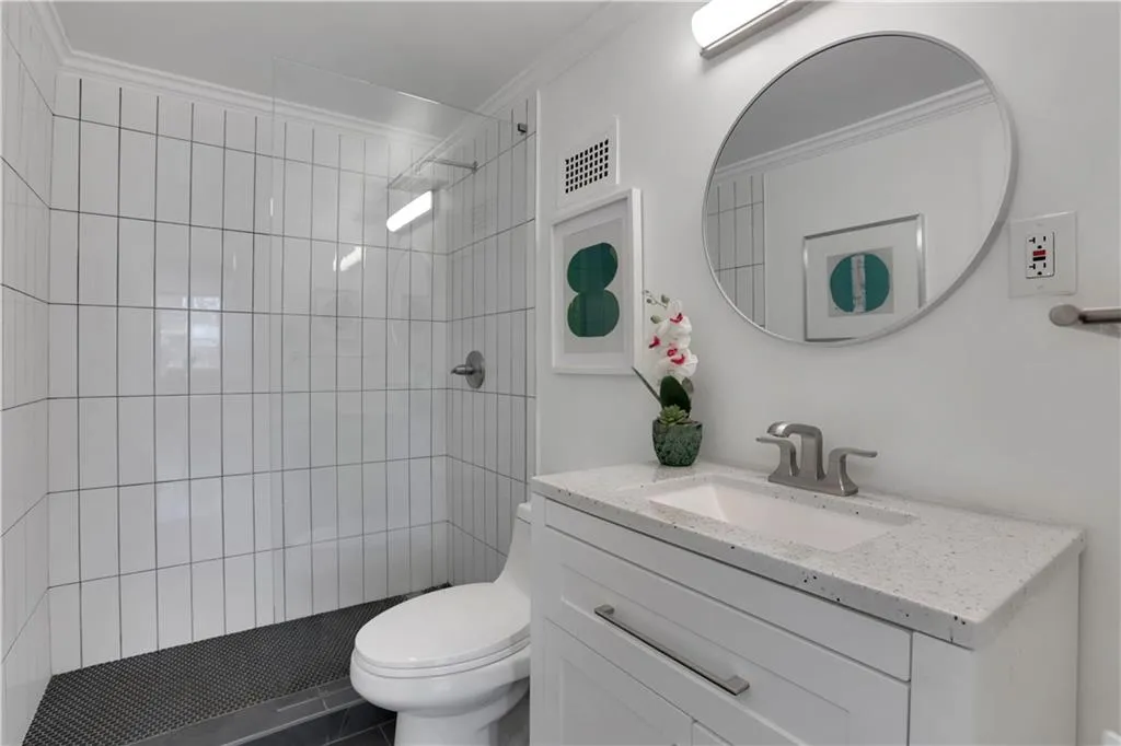 Full bathroom featuring tiled shower, vanity, and ornamental molding