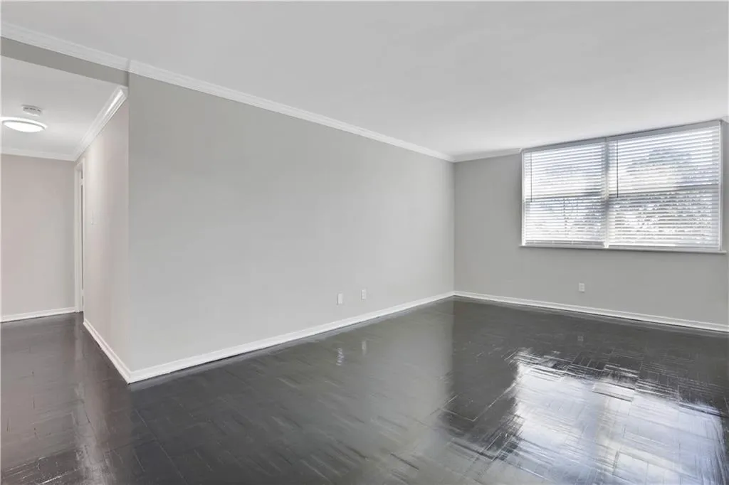 Empty room featuring ornamental molding and dark wood-style floors