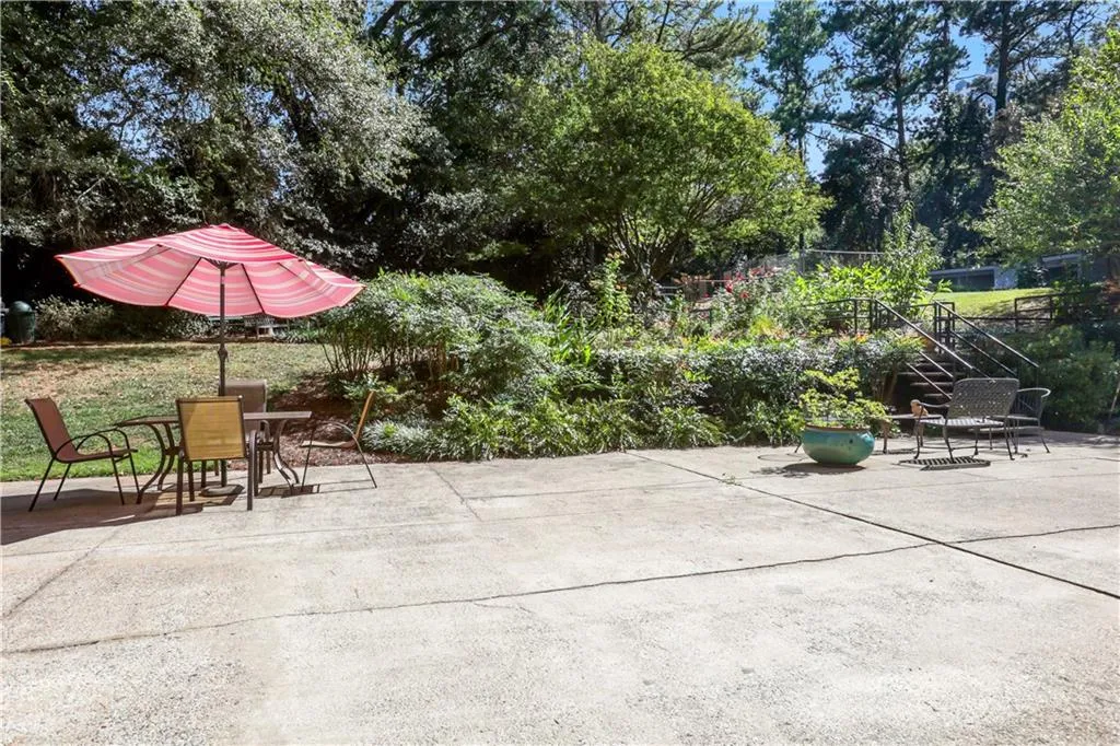View of patio with outdoor dining area, stairway, and view of wooded area