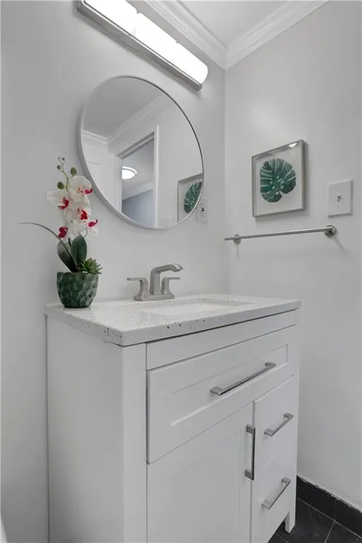 Bathroom featuring vanity, crown molding, and dark tile patterned floors