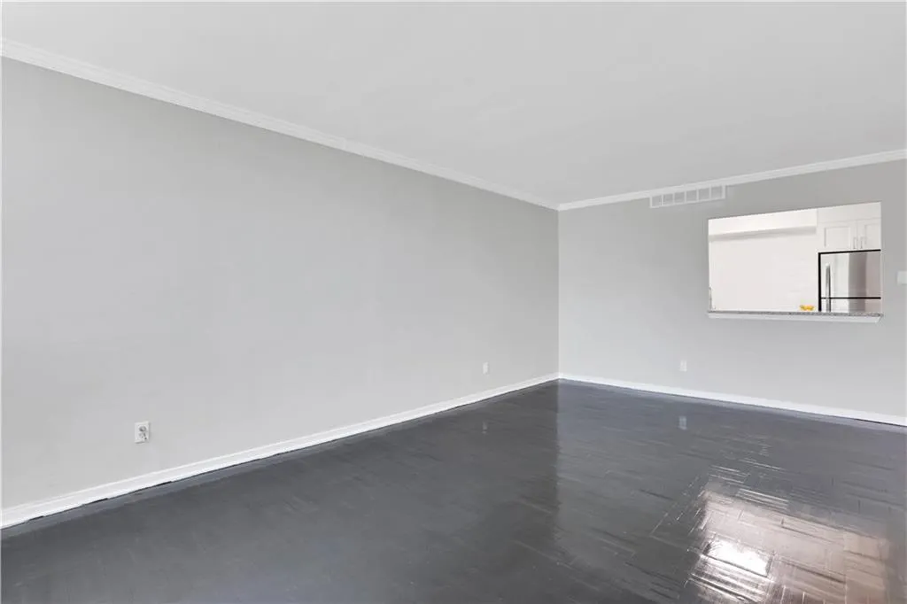 Spare room featuring ornamental molding and dark wood-type flooring