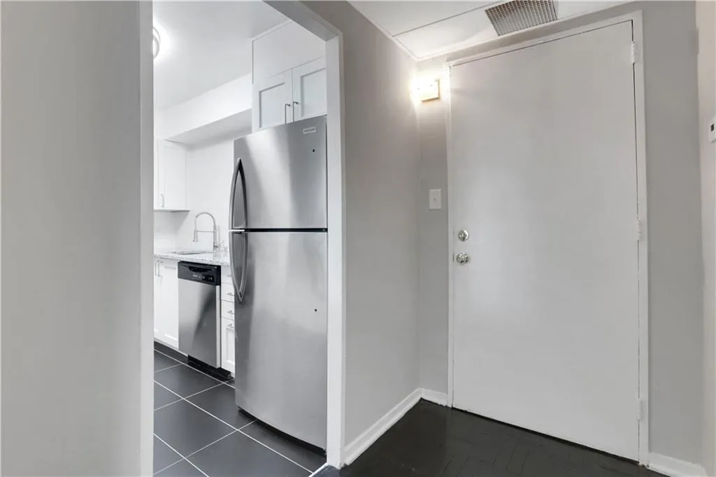 Kitchen featuring white cabinetry, appliances with stainless steel finishes, and light stone counters