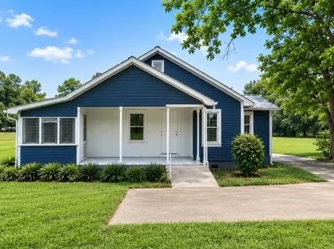 Charming blue exterior featuring white trim, a covered front porch, and a screened-in sunroom